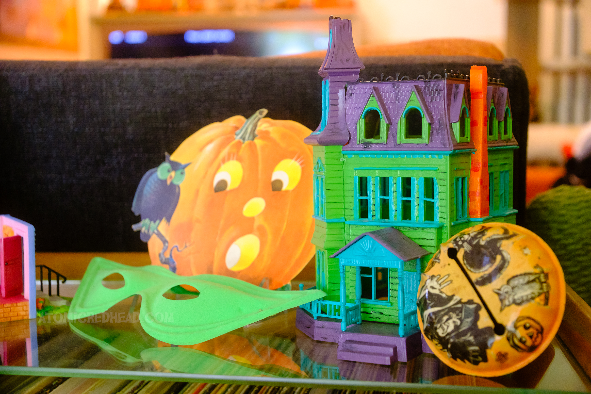 Close-up of a small plastic haunted house painted green, purple, and turquoise. 