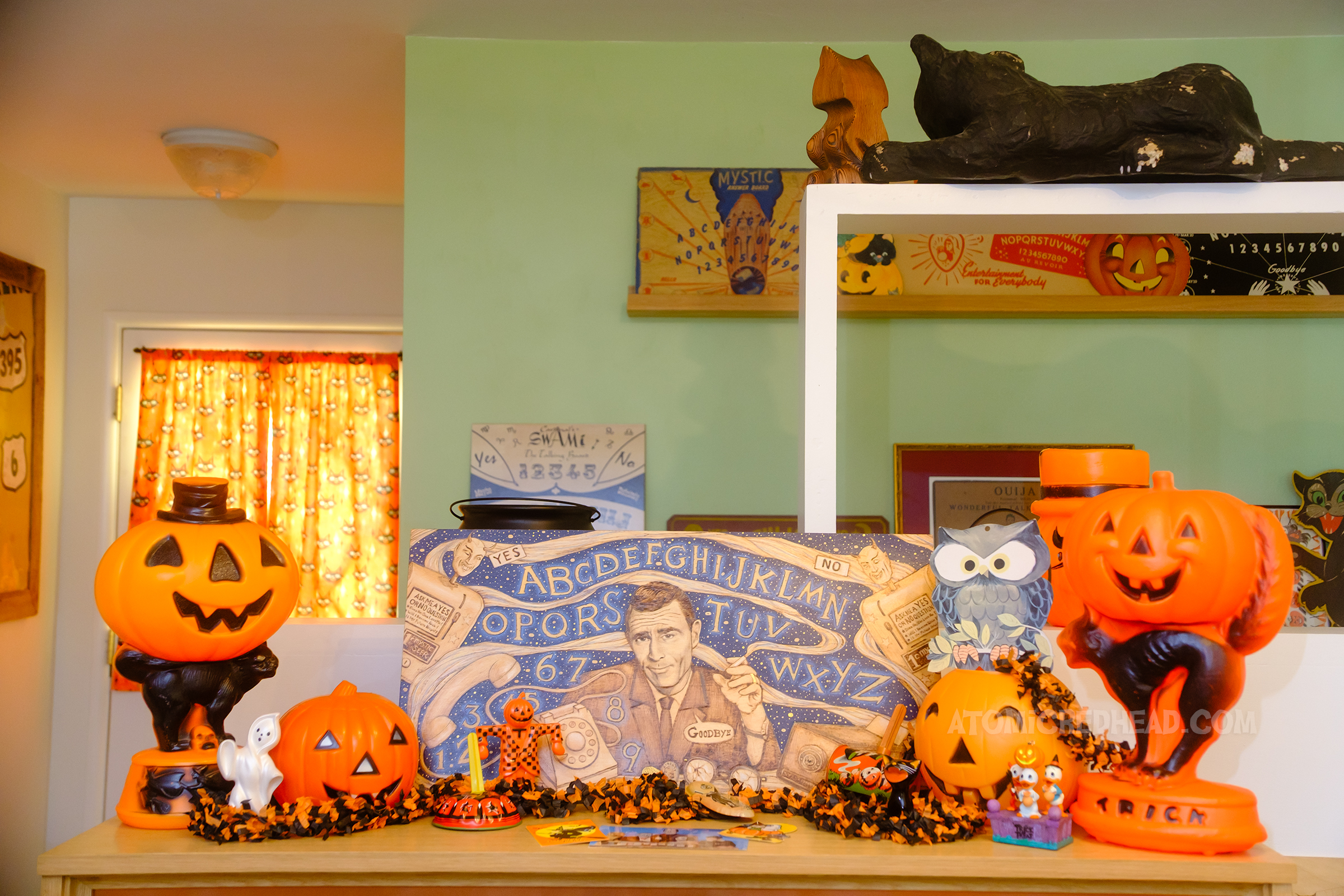 Close-up of the display on top of our TV where a spirit board with a Twilight Zone theme, featuring Rod Serling and icons from the show is surrounded by vintage plastic jack o'lanterns.