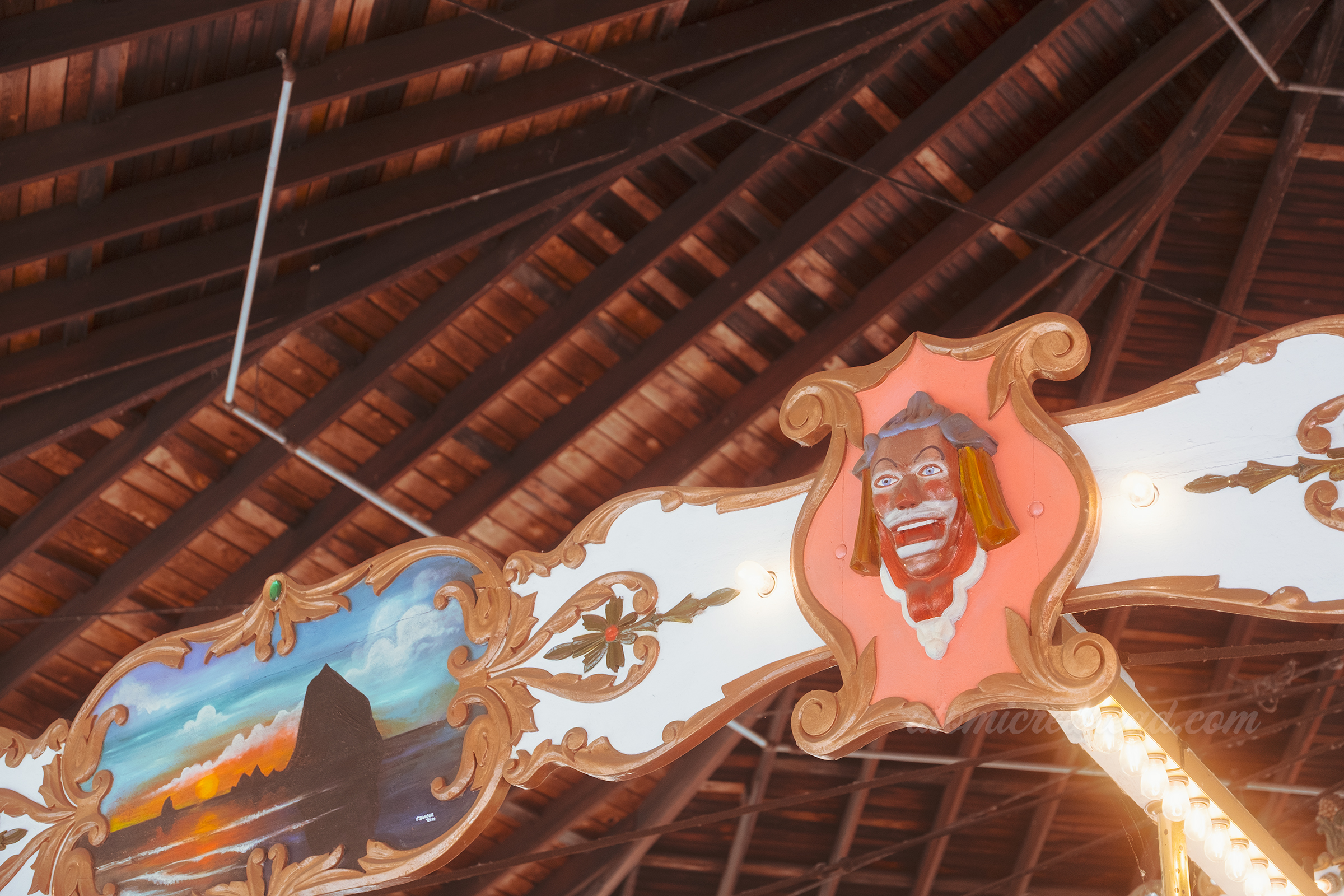 A clown face and a painted image of Haystack Rock on the top of the carousel edge.