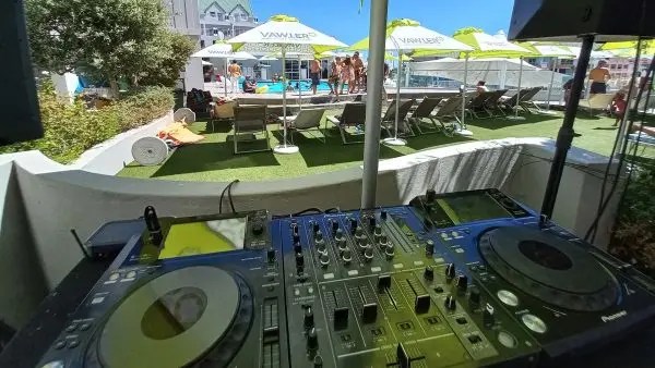 Audio Elite's DJ booth setup overlooking a hotel pool party in Gordons Bay, with premium sound and lighting services