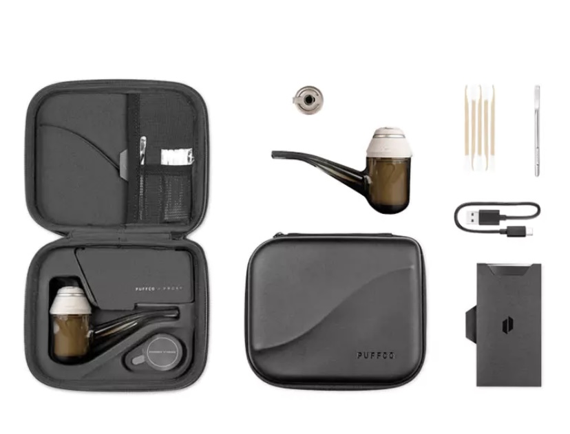 Puffco travel kit for a concentrate rig: open case showing the main device, mouthpiece, glass bowl, and tools with a closed carrying case and USB charging cable nearby.