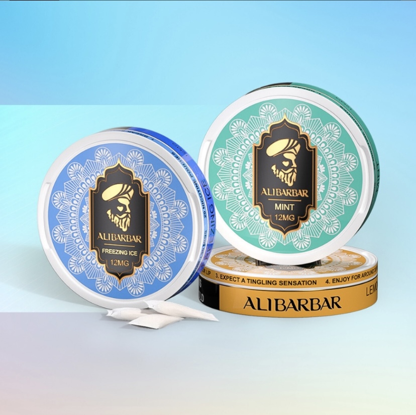 Two Round Mint Tins with Ornate Teal and Blue Designs Alibarbar Mint 12mg Plus White Sachets on a Pastel Surface - Australia E-cigarette Store