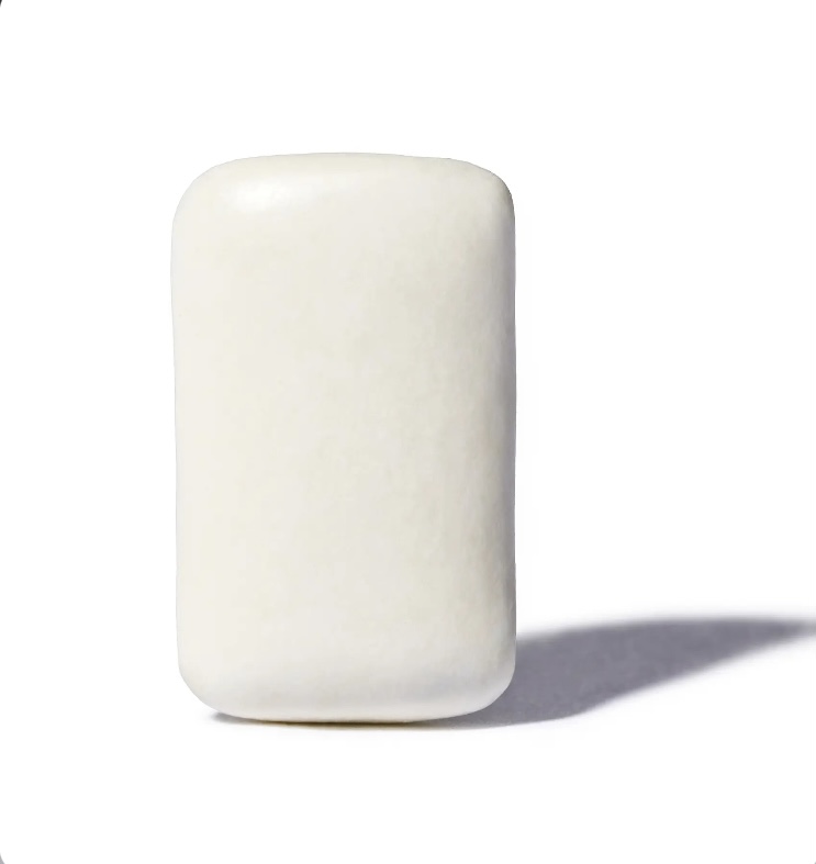 A single white marshmallow standing upright on a white surface with a soft shadow to the right.