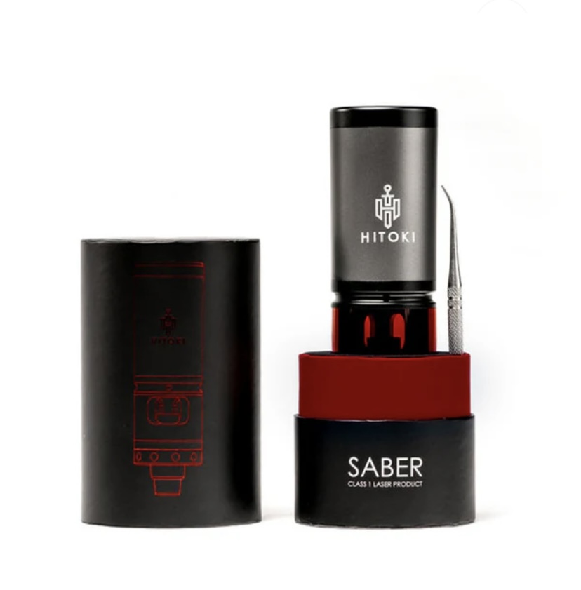 Hitoki Saber laser device with gray top, red cradle, and black base, shown next to its black box.
