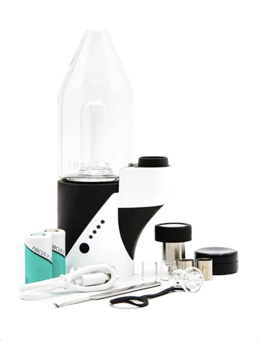 Vape starter kit with glass tank, black-and-white mod, coils, USB charger, and small accessories laid out on a white background.