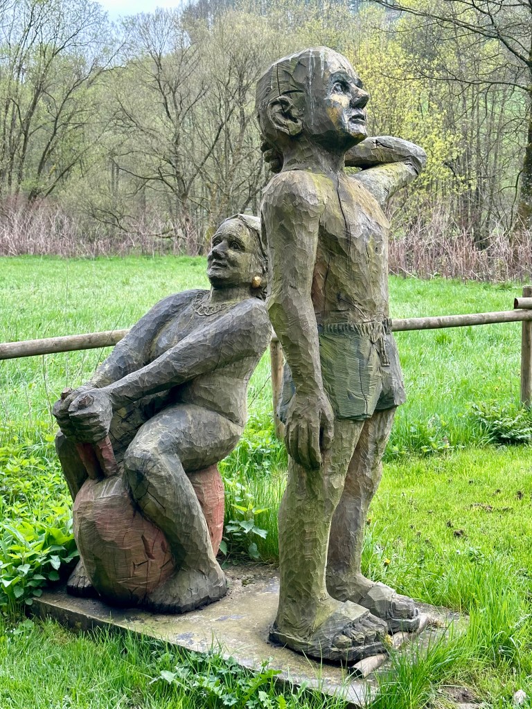 Holzskulpturen „Badegäste“ von Roger Löcherbach am Ufer der Lenne