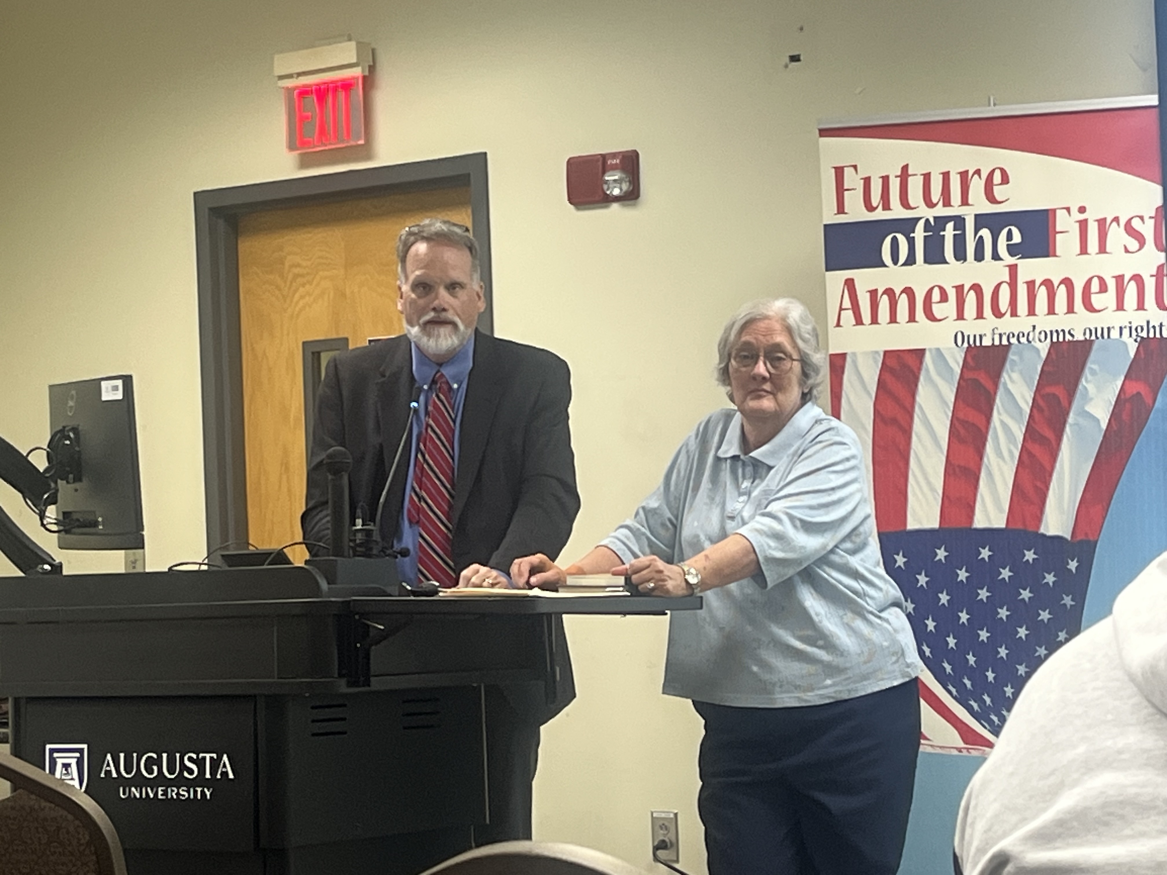 A man and woman stand behind a podium