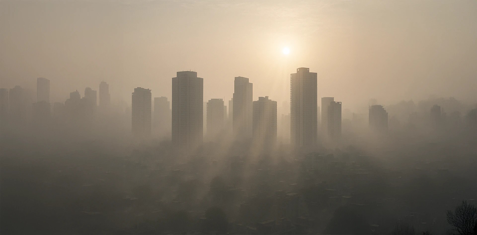 Dense morning smog covering a city skyline after Diwali, with sunlight filtering through high-rise buildings — a real example of air stagnation observed through Real-time Pollution Monitoring After Diwali.