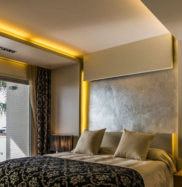 A strip light installed along the ceiling of a bedroom, casting a warm yellow glow.