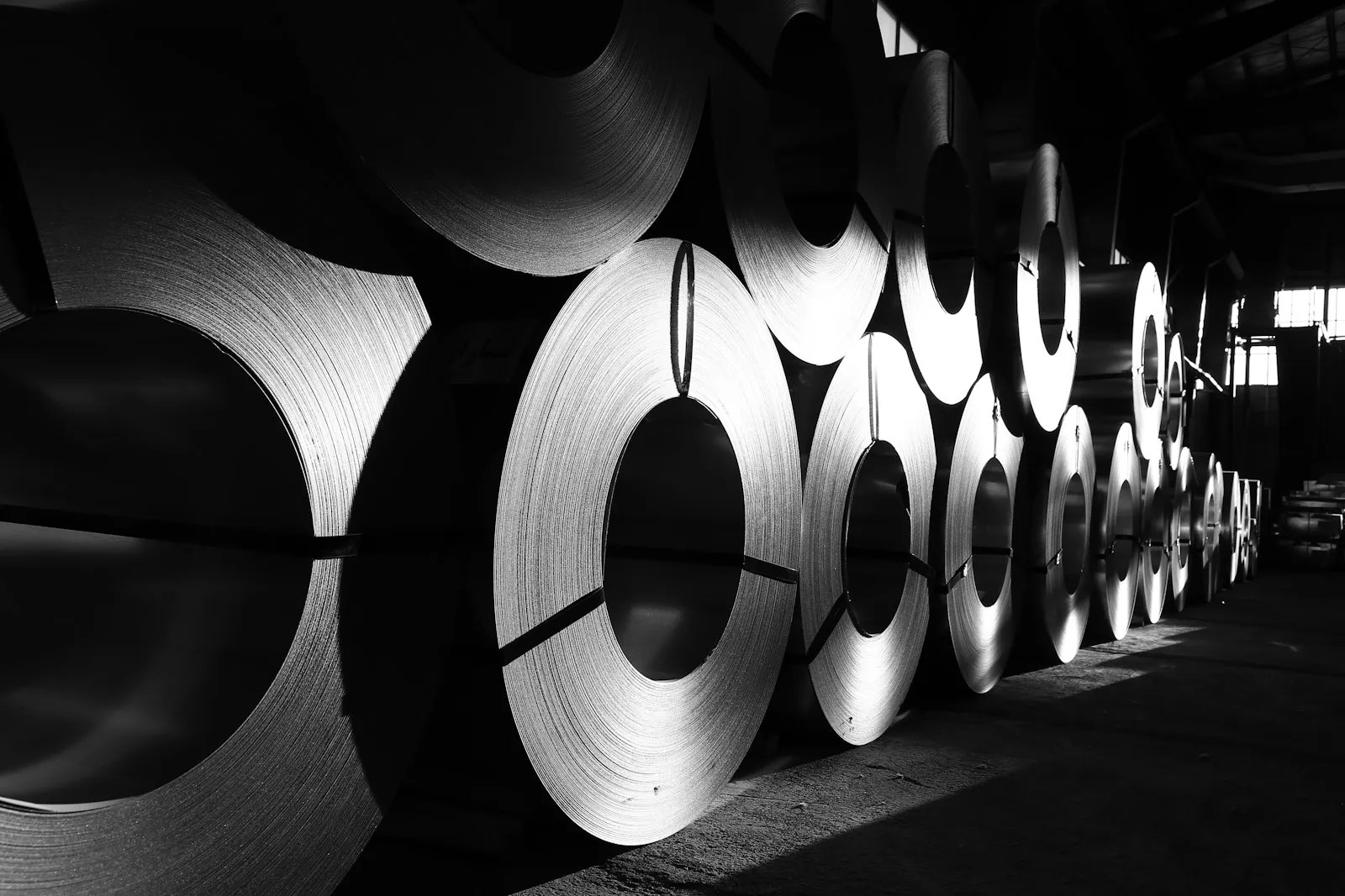 Rolls of steel lined up in a warehouse ready for machining