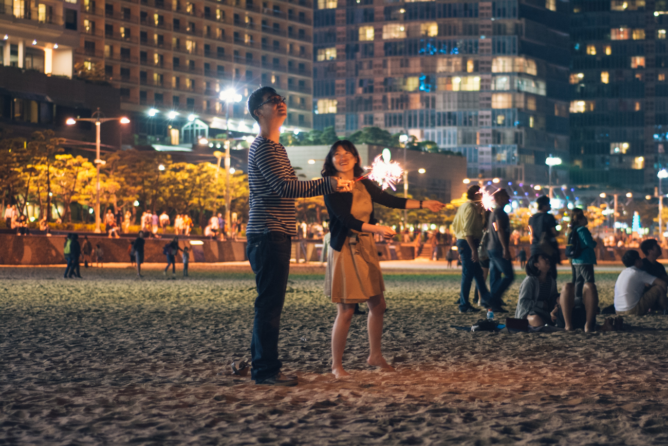A Korean couple sets off fireworks at Haeundae Beach at night
