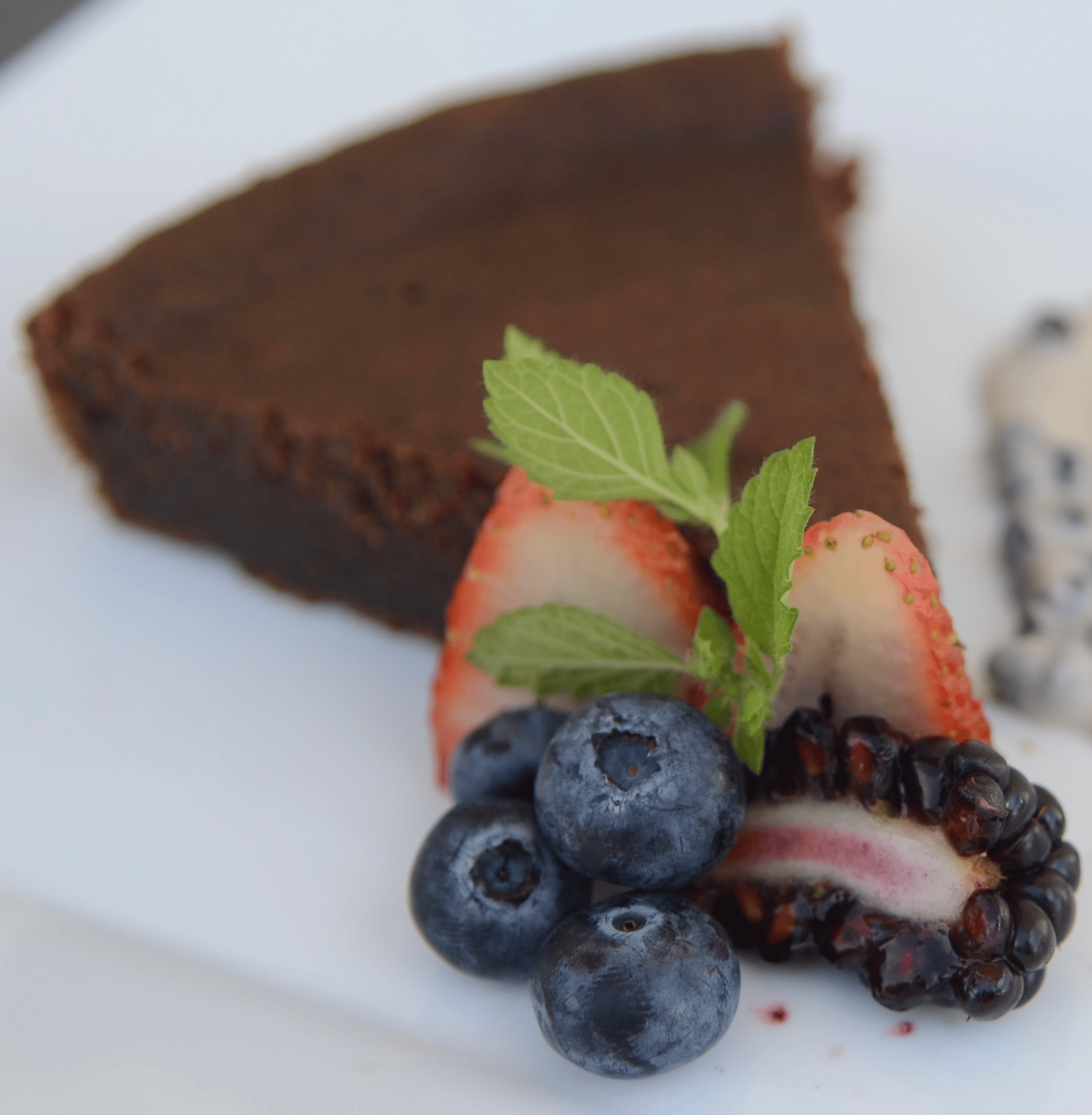 Slice of Jamaican black cake served with fresh berries and mint, prepared by Chef Nadine.