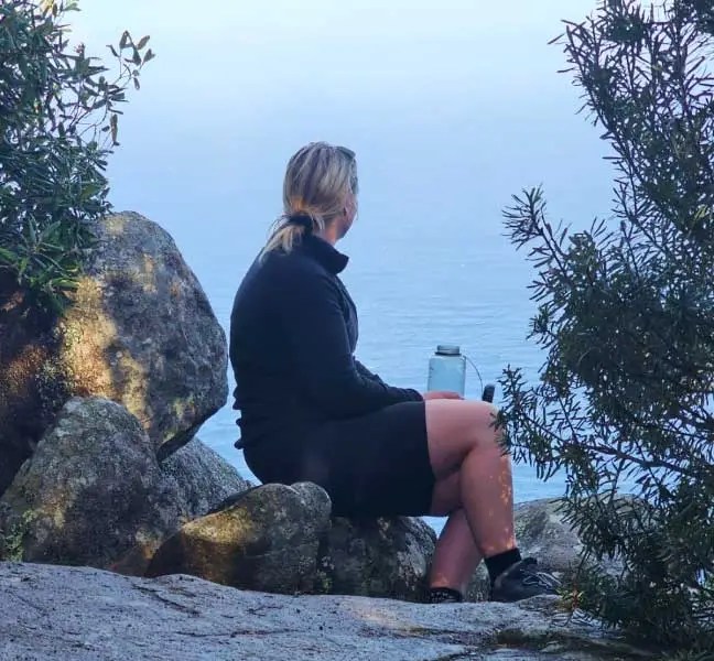 Lady sitting on a rock over looking the ocean in Tasmania.