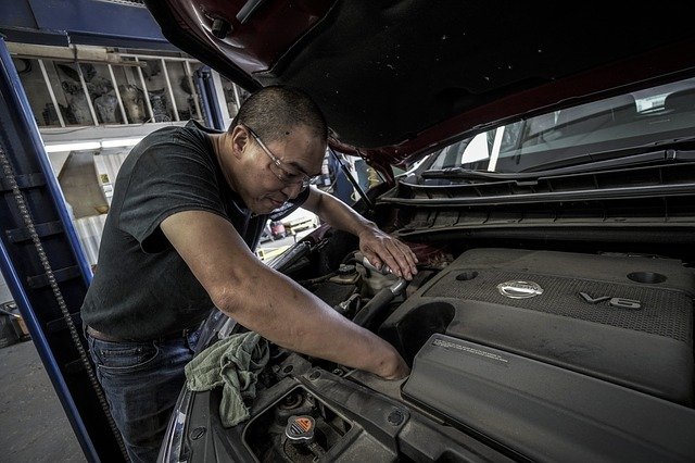 Car mechanic checking engine oil
