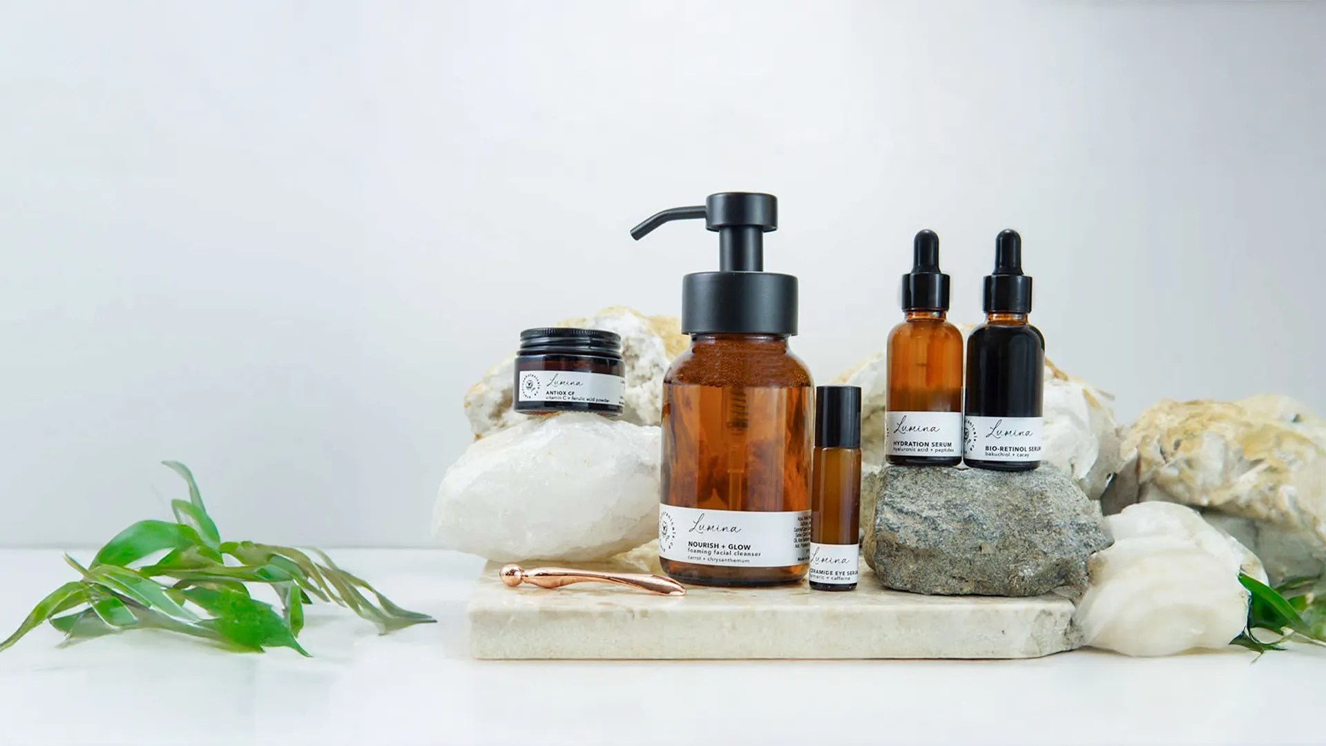 Skincare Set displayed on crystals and marble table serums and foaming face wash in Amber glass apothecary bottles on a marble table