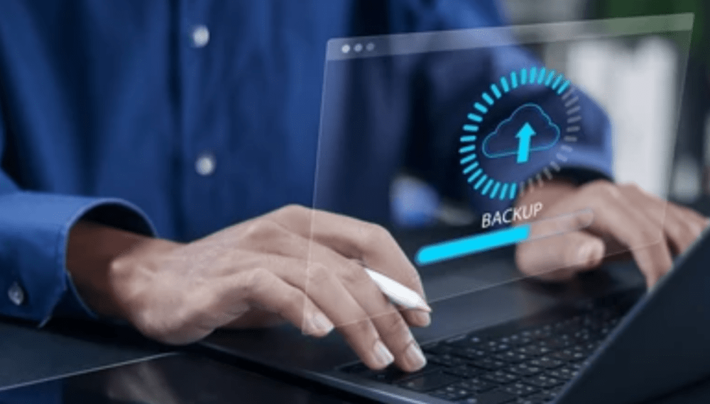 A person using a laptop initiates a backup, illustrated by a digital overlay showing a cloud upload icon, a progress bar labeled "BACKUP," and hints of easy recovery options seamlessly integrated into the interface.