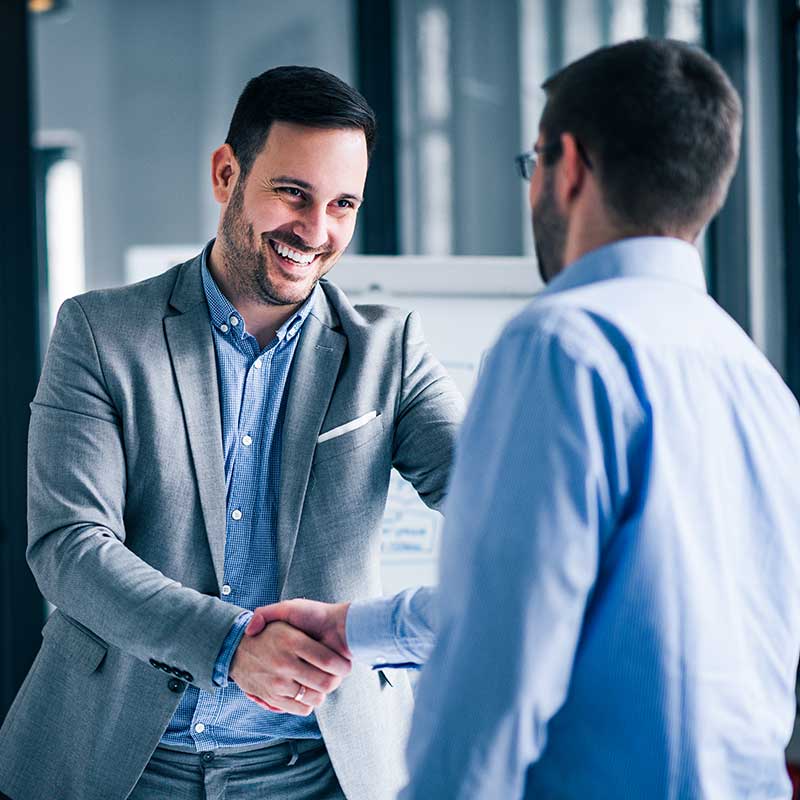 Two professionals engaging in a friendly handshake in a modern office setting.