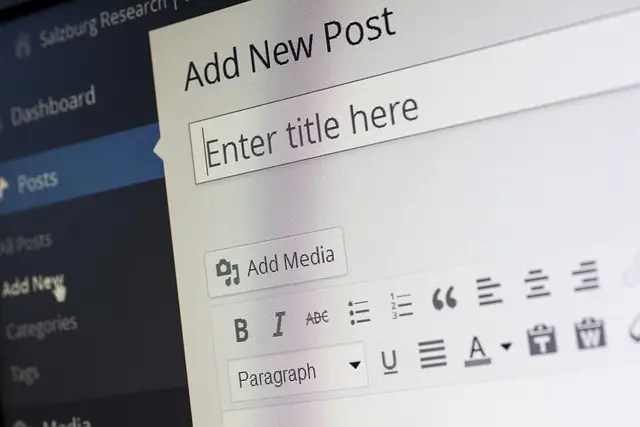 A computer screen displays the WordPress editor with the Add New Post page open, illustrating How to Create a WordPress Blog Post with AVI Lead Gen Builds, featuring title and content fields alongside formatting and media options.