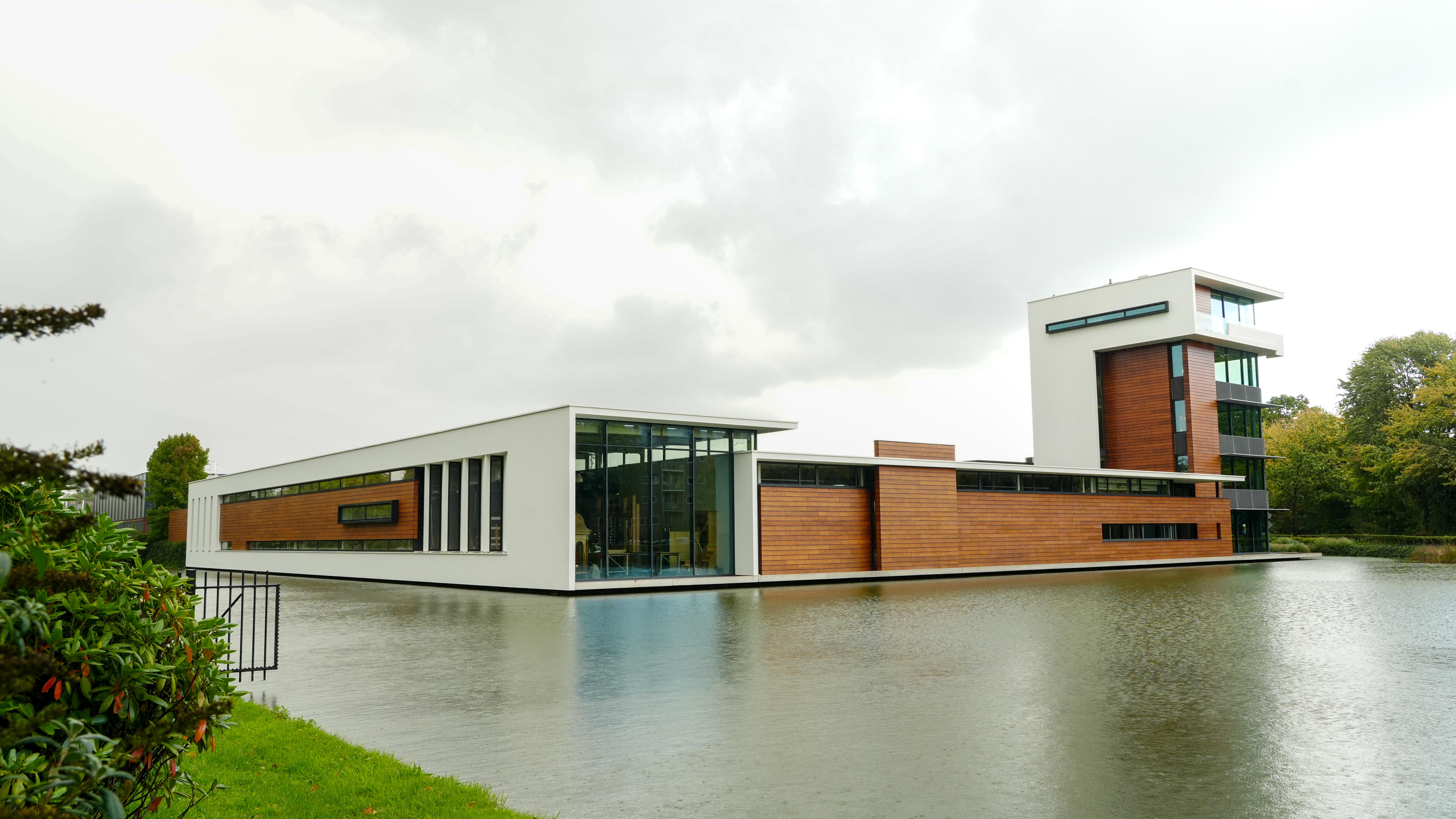 Modern gebouw met houten gevel en grote ramen aan het water