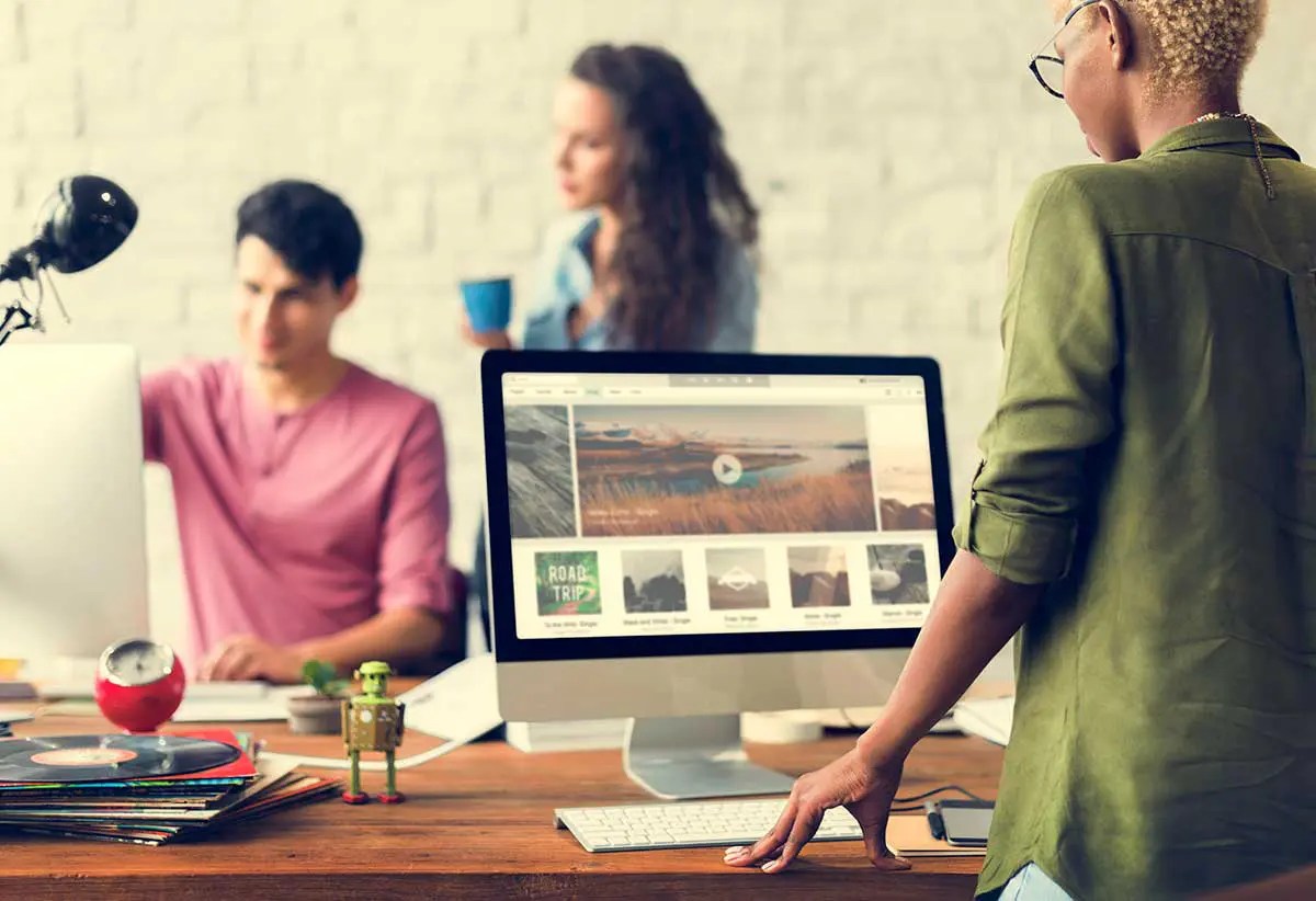 Business team collaborating in a modern workspace with a website displayed on a desktop monitor