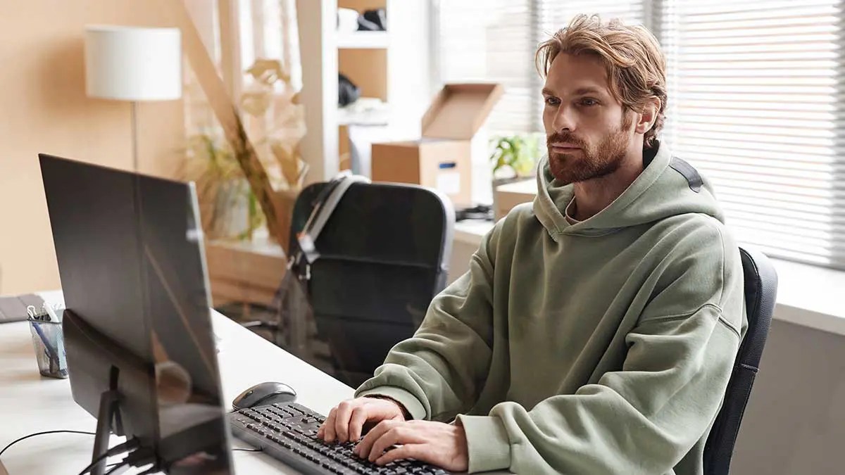 A person typing on a laptop at a cozy workspace with a notebook, coffee mug, and small potted plants, symbolizing the 7 creative blogging tips.