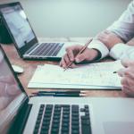 Two business professionals utilize proposal management software on laptops