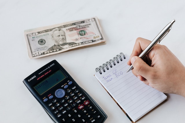 Calculator, $20 bill, and notepad representing savings and financial planning