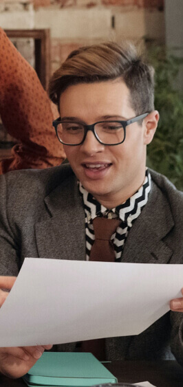 Person reading a document in a professional setting, wearing glasses and a stylish outfit, relevant to B2CAds' digital marketing services.