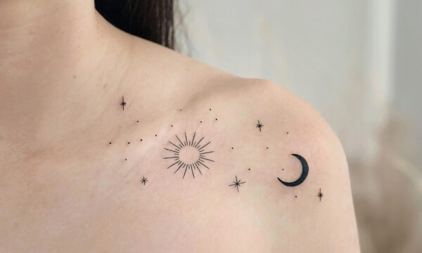 Fine line celestial tattoo featuring a sun, crescent moon, and scattered stars across the collarbone and shoulder