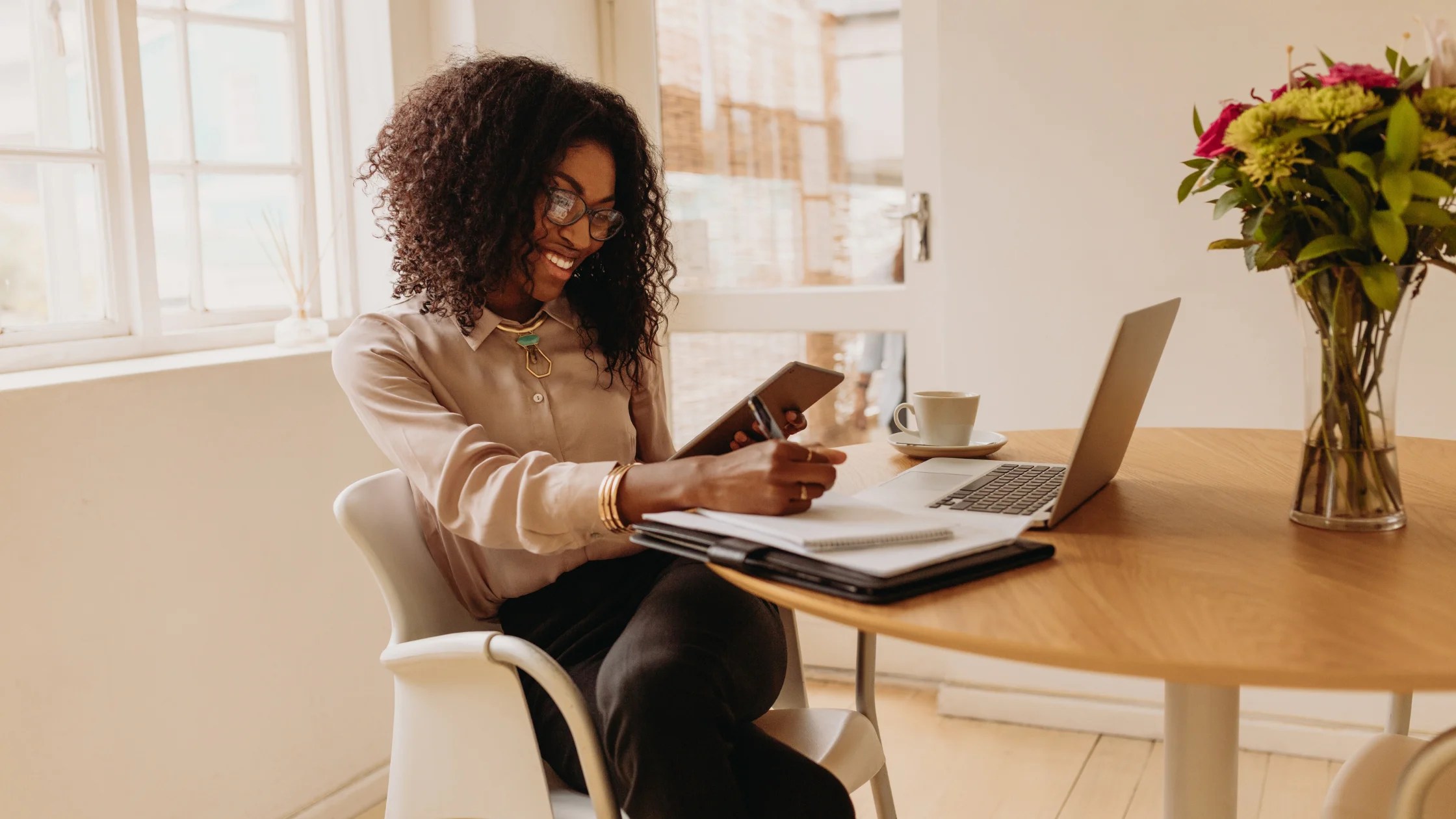 woman on tablet writing down on paper