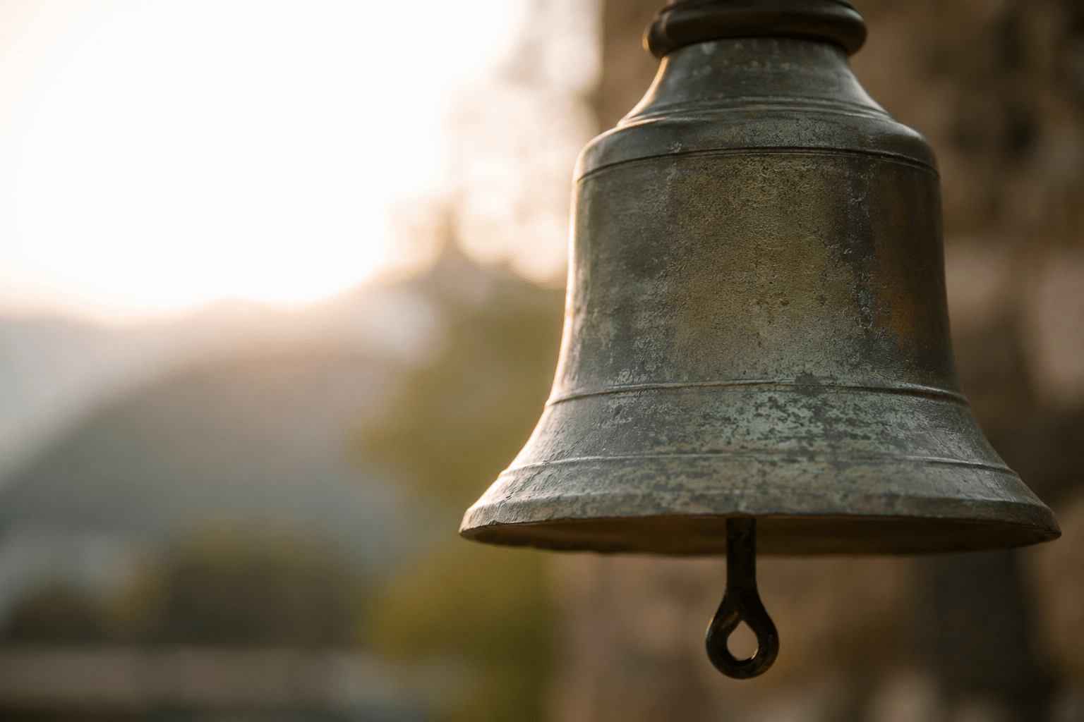 Weathered bronze bell in warm morning light, symbolizing the enduring role of sound in spiritual traditions and creation stories.