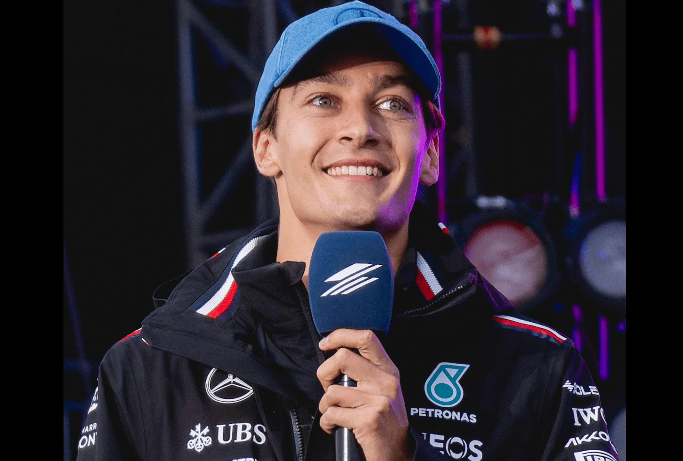 George Russell smiling during an interview in his Mercedes F1 team gear