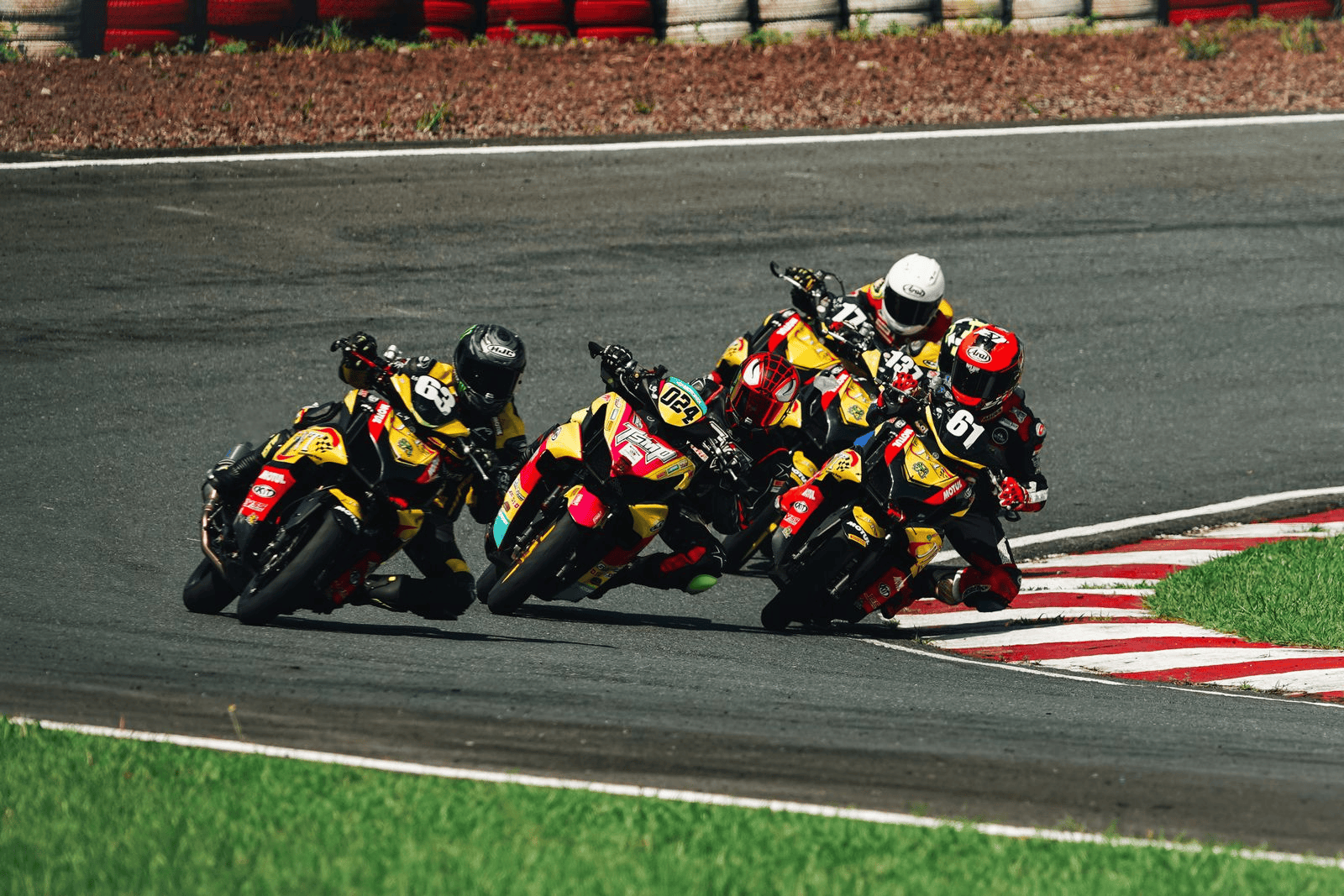 A pack of motorcycle racers in yellow and black leathers leaning through a corner on a racing circuit