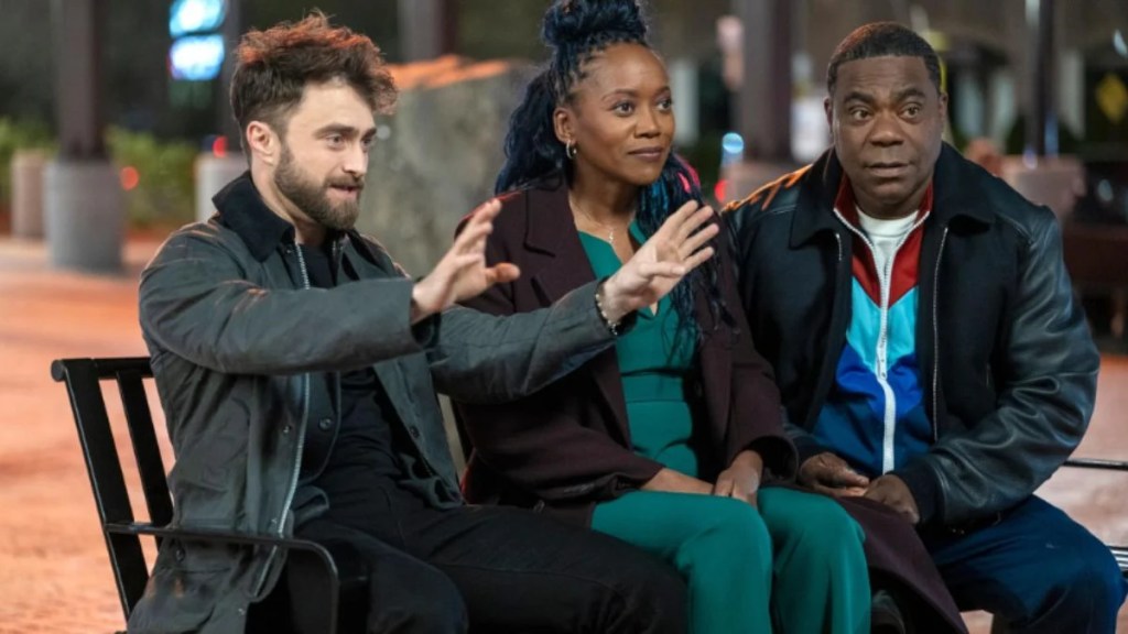 Tracy Morgan in a blue tracksuit facing off with Daniel Radcliffe in a doorway.
