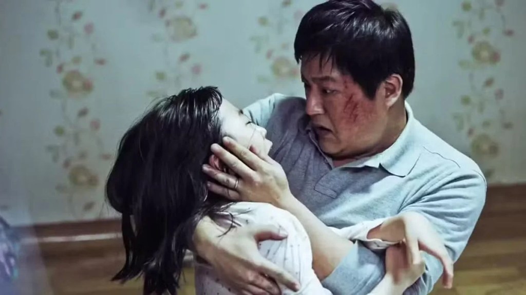 Jong-goo holding his possessed daughter Hyo-jin in a scene from The Wailing.
