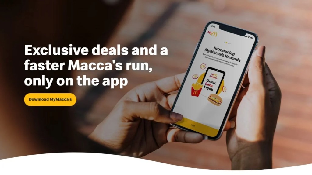 A person holding a smartphone showing the MyMacca's Rewards program interface