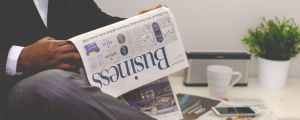 our-services-2 Businessman reading a financial newspaper at a desk, highlighting finance and commerce theme.
