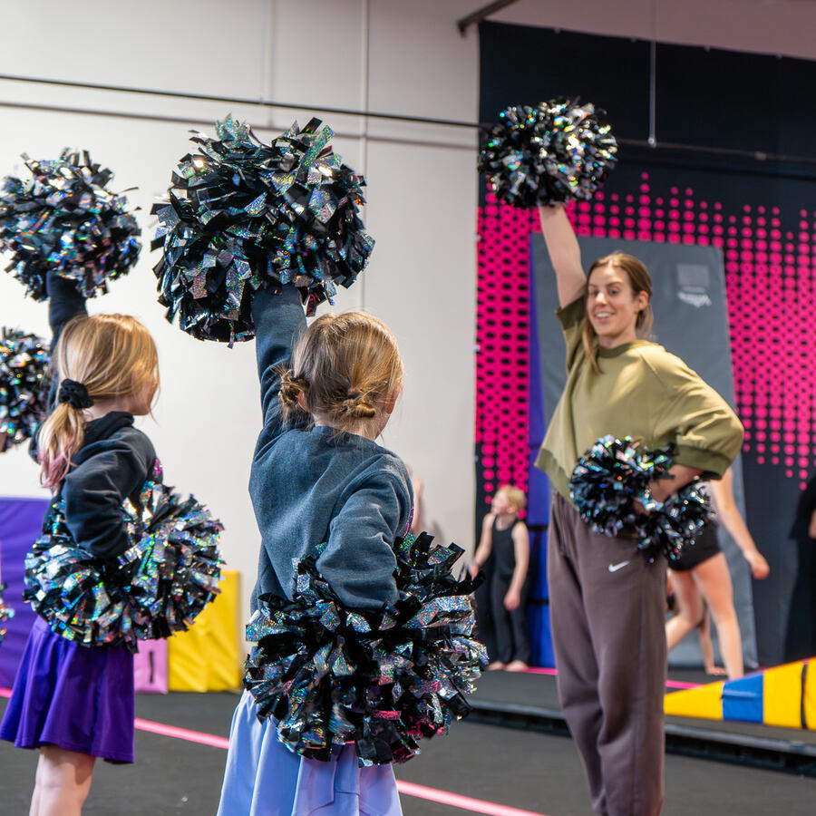 Recreational cheer athletes practicing pom motions