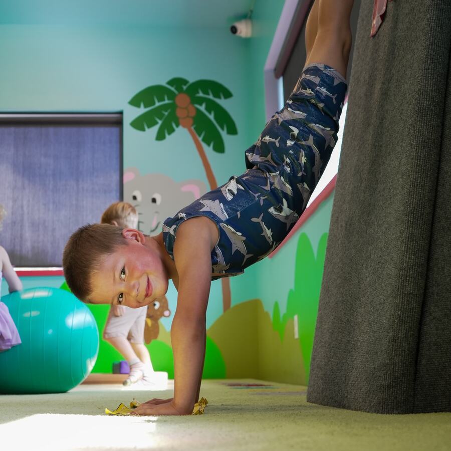 Young boy doing a handstand in Bailey's Sports' jungle-themed Tots gym