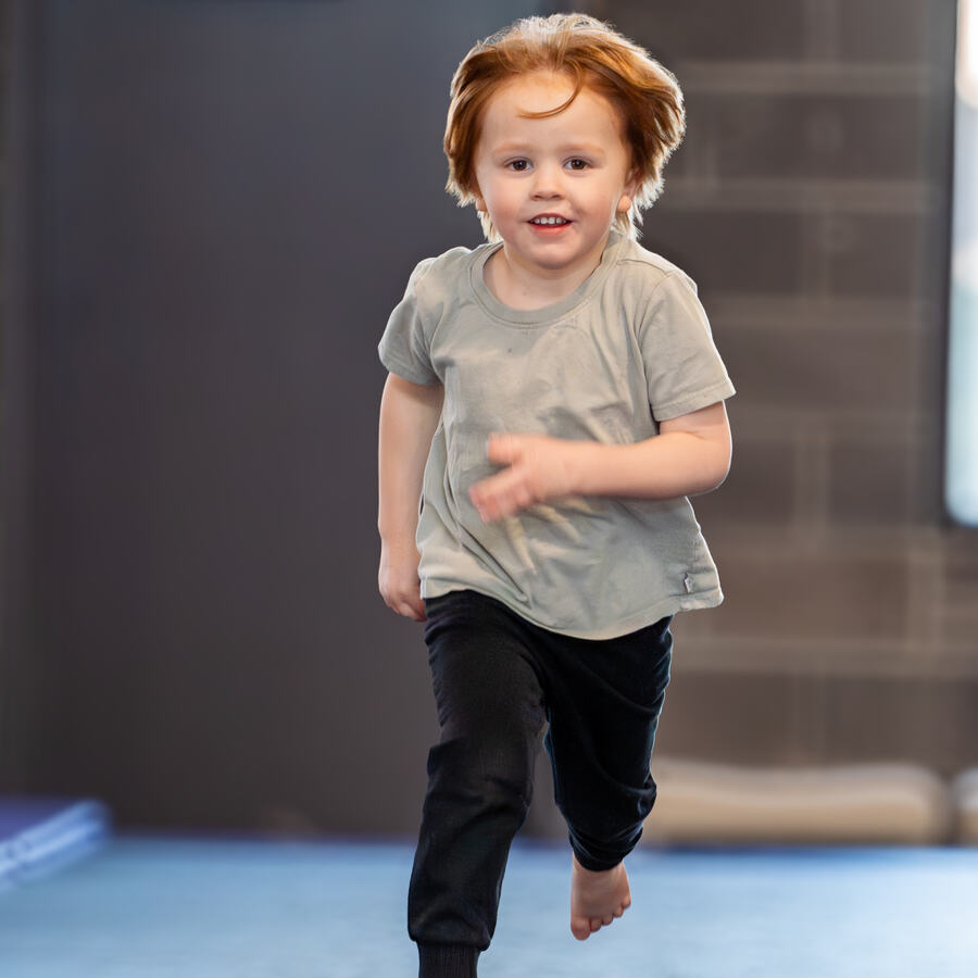 Toddler running and smiling during Tots Camp