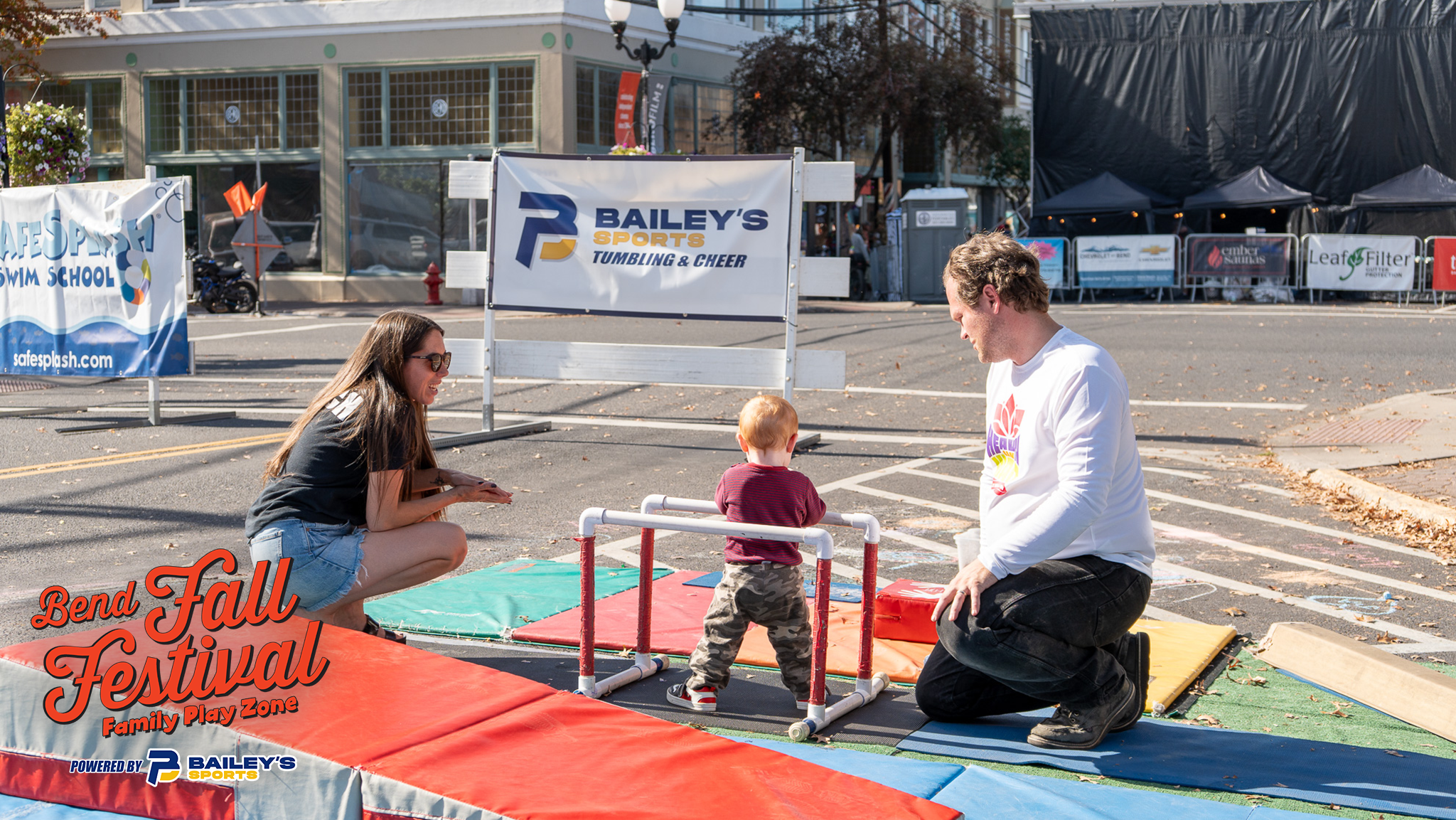 Bailey's Sports staff talking with families beside the obstacle course at Bend Fall Fest