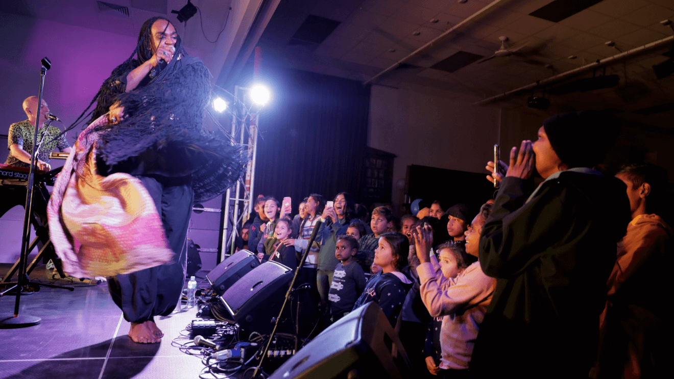 A performer on stage with the audience dancing on the right side