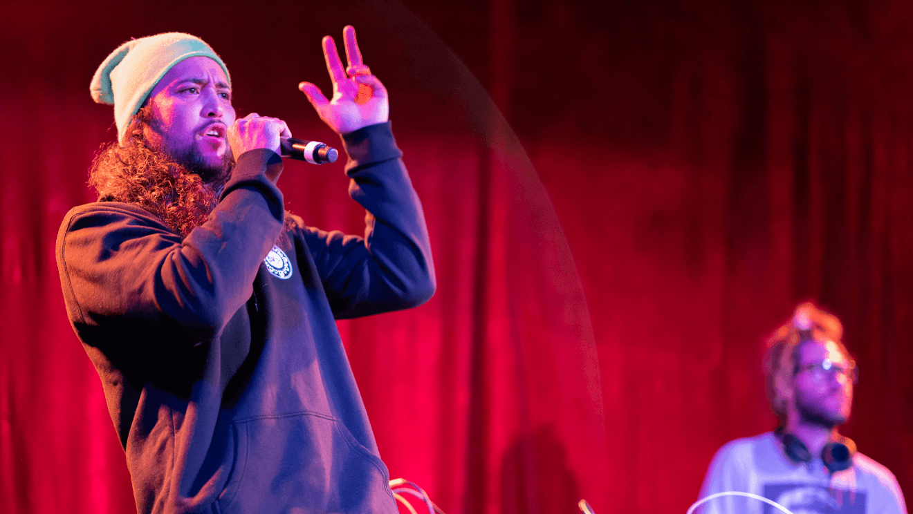 a close up of a singer holding a microphone, he is gesturing with his left hand