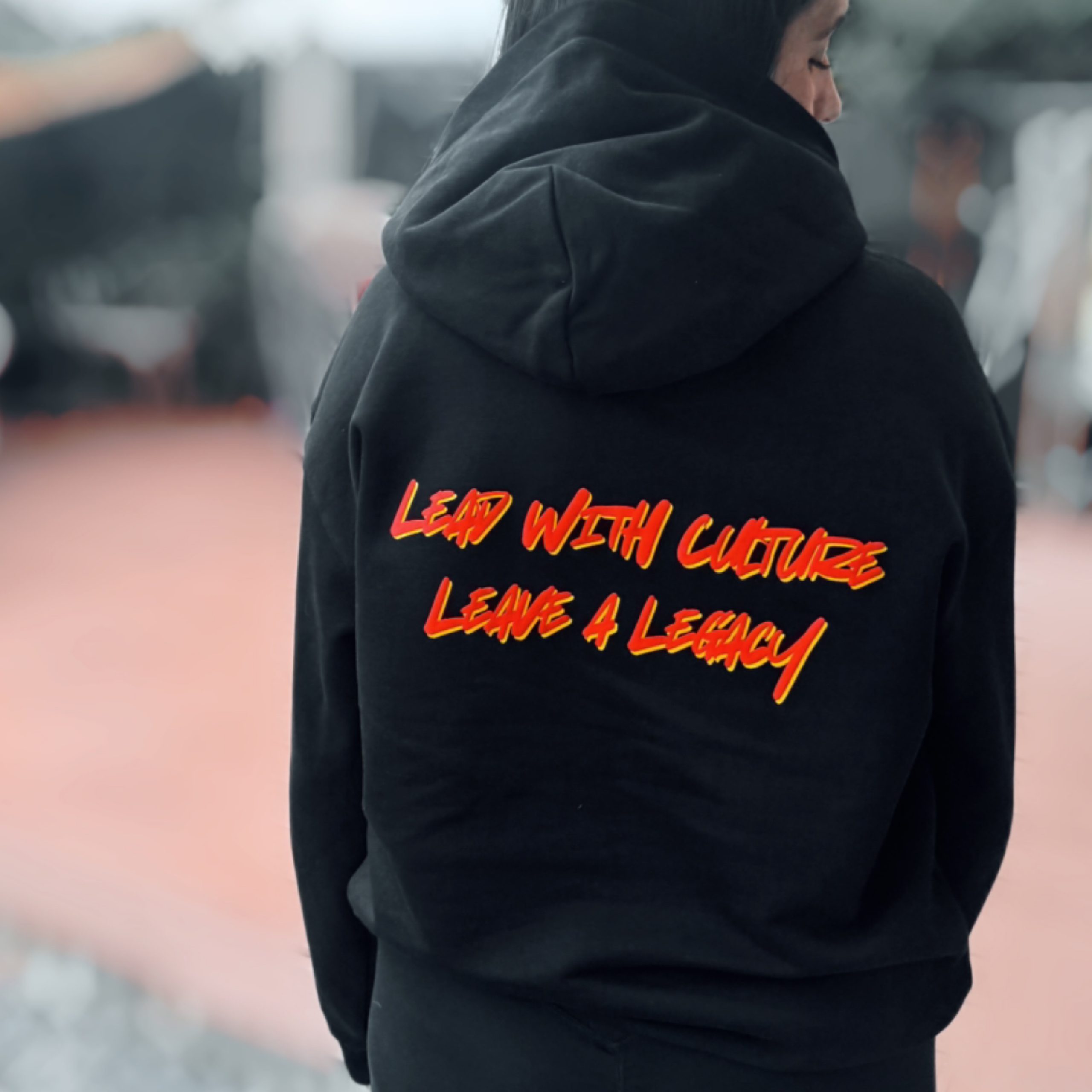 Black hoodie bag with red and yellow 'lead with culture, leave a legacy' print