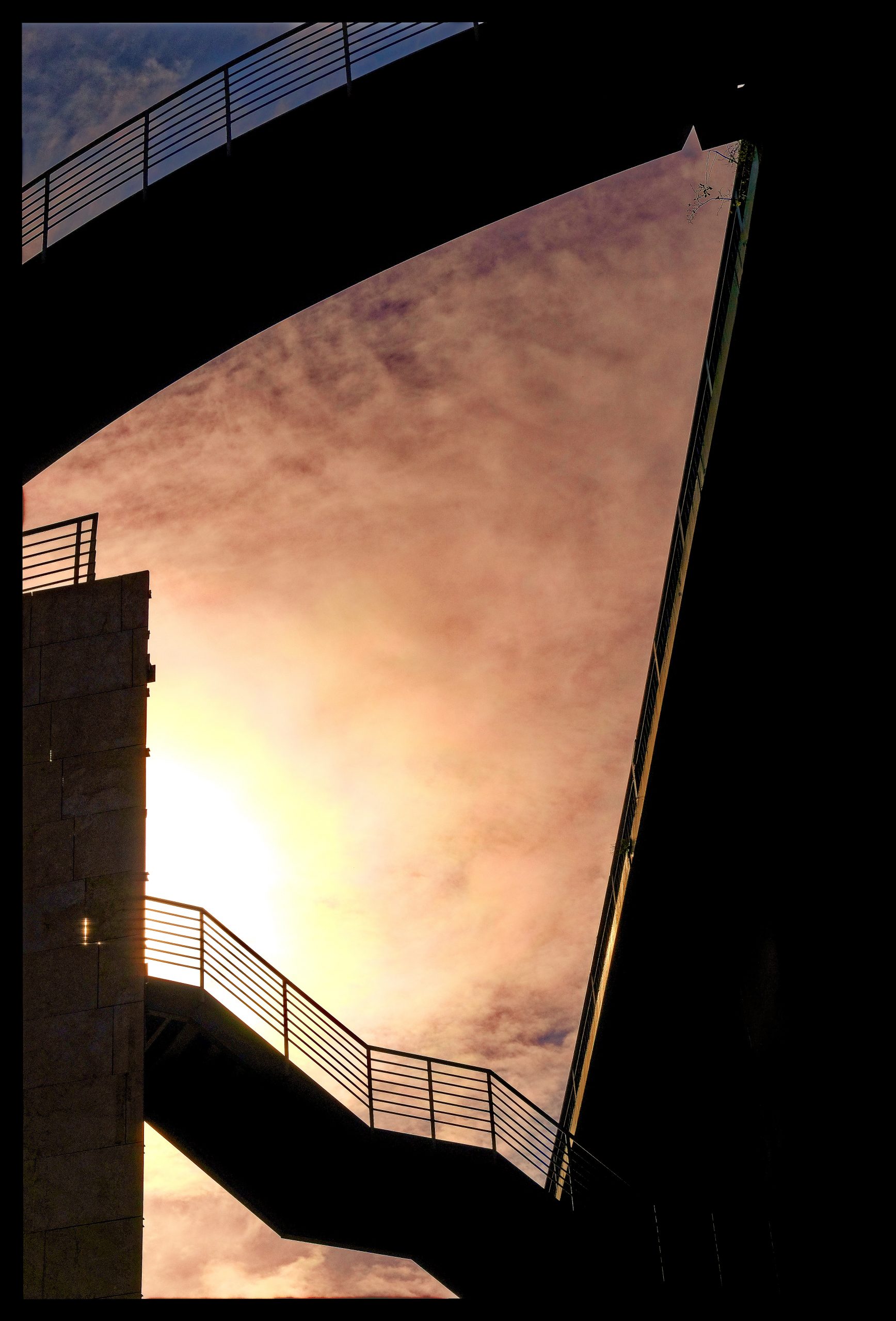 a bridge with railings and a pink sky