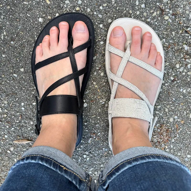 Top view of Proalp Terra black and gold leather barefoot sandals with criss-cross straps, worn on feet while standing on pavement