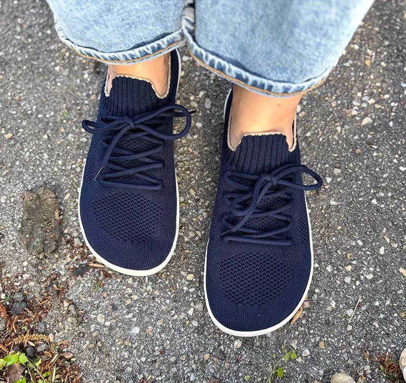 Top view of Shapen Weavin navy barefoot sneakers with knit upper, worn with rolled-up jeans on pavement