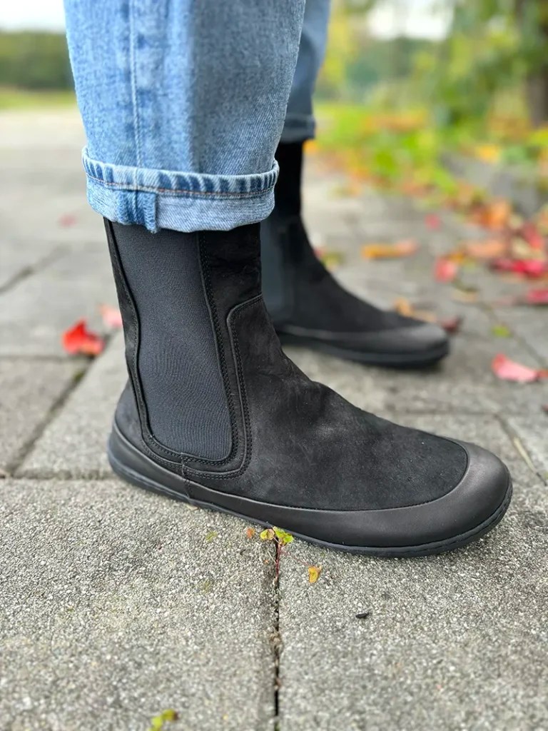 Black barefoot Chelsea boots, paired with rolled-up jeans.