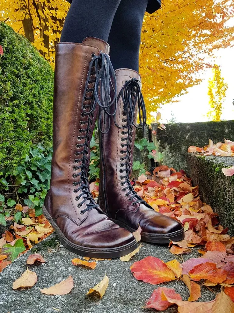 Tall brown lace-up barefoot boots in autumn leaves