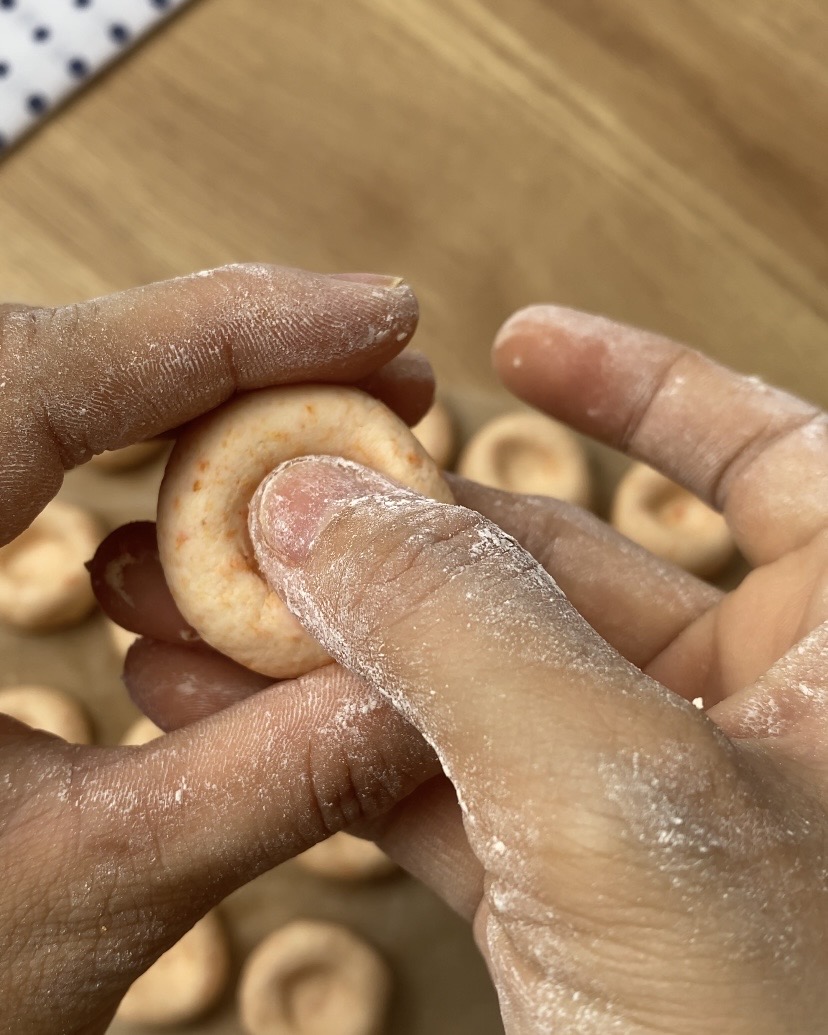 Pressing a thumb into carrot dough to shape chewy carrot button noodles
